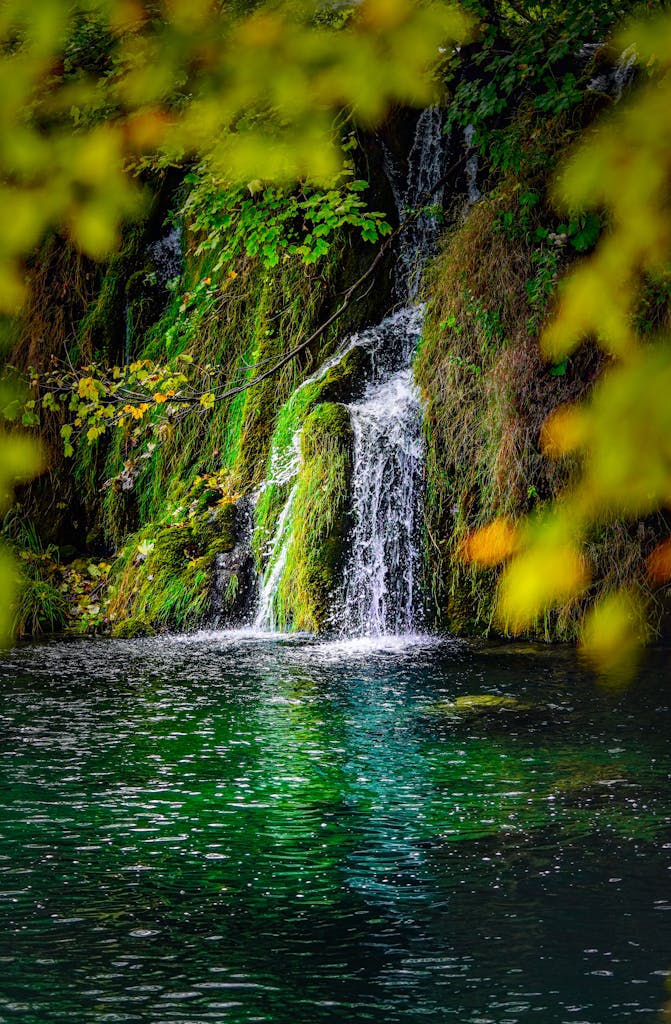 A tranquil waterfall cascading into a clear pond, surrounded by lush greenery in Croatia.