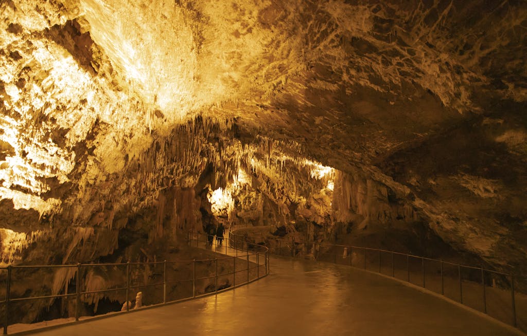 Explore the stunning formations of Postojna Cave in Slovenia, showcasing dramatic stalactites and lighting.